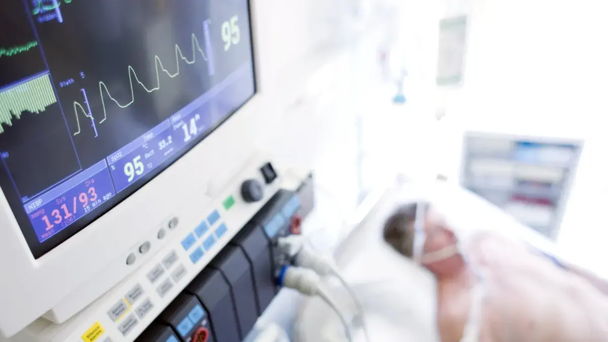 A patient on a hospital bed being monitored on a life support machine