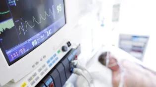 A patient on a hospital bed being monitored on a life support machine