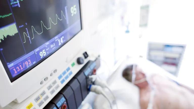 A patient on a hospital bed being monitored on a life support machine