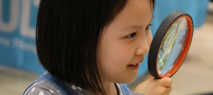 Girl holding up a magnifying glass
