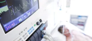 A patient on a hospital bed on a life support machine being monitored.