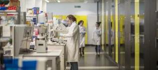 scientist pipetting in a lab with some yellow doors