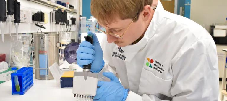 Researcher pipetting something in a lab in a white lab coat