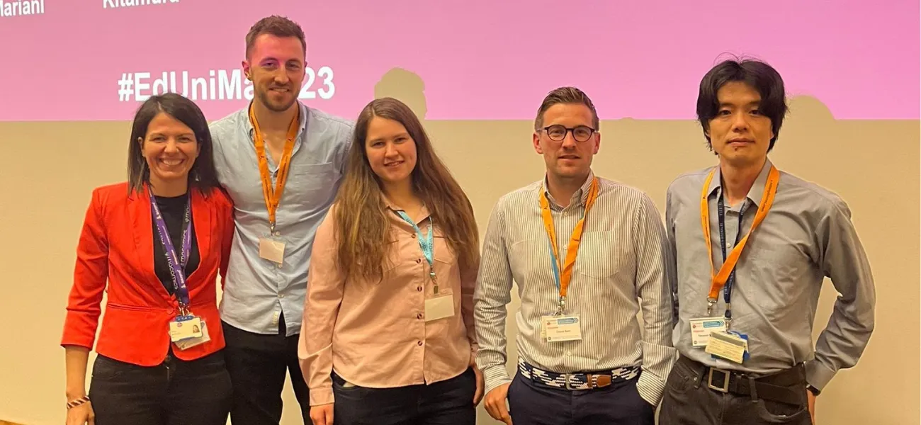 5 conference organisers standing in front of a large screen