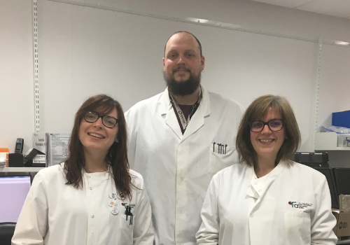 Mari George, Will Ramsay, and Shonna Johnston wearing lab coats, smiling in a lab